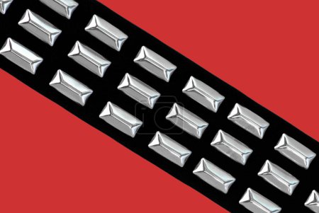 Foto de Cinturón de cuero negro con clavos de cromo sobre un fondo rojo - Imagen libre de derechos