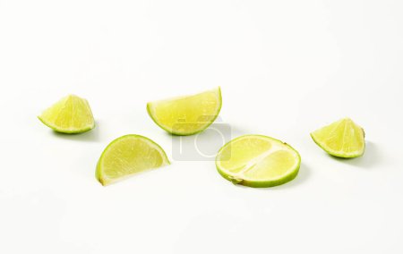 Téléchargez les photos : Morceaux de citron vert frais sur fond blanc - en image libre de droit