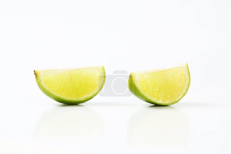 Photo for Two lime fruit quarters on white background - Royalty Free Image