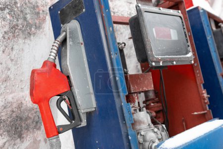 Old gas dispenser. Abandoned fuel pump with red fuel nozzle. Energy crisis concept