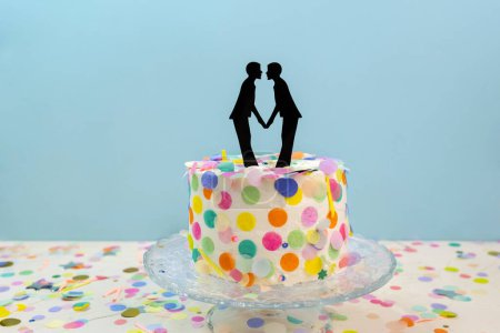 Two grooms cake toppers on decorated wedding cake. Newlywed figurines decoration on wedding cake for gay wedding. Gay wedding concept LGBTQIA