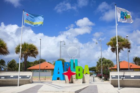 Téléchargez les photos : ORANJESTAD, ARUBA - 17 JUILLET 2022 : Panneau Aruba coloré avec des drapeaux Aruba sur la Plaza Turismo à Surfside Beach à Oranjestad sur l'île caribéenne d'Aruba (Focus sélectif, Focus sur le devant de l'image) - en image libre de droit