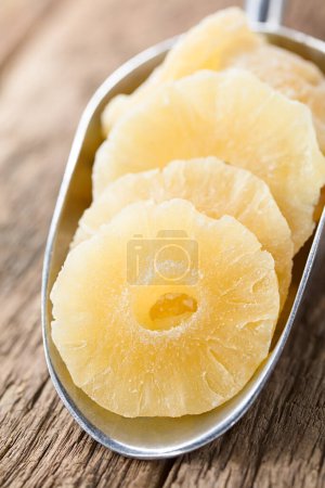 Photo for Candied or glac pineapple slices in metal scoop on wood (Selective Focus, Focus diagonally through the middle of the first slice) - Royalty Free Image