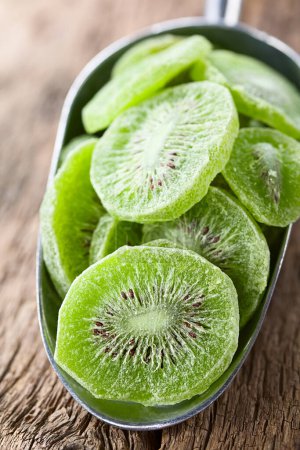 Photo for Candied or glace kiwi fruit slices in metal scoop on wood (Selective Focus, Focus through the middle of the first slice) - Royalty Free Image