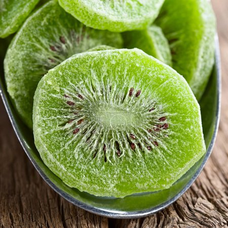 Photo for Candied or glace kiwi fruit slices in metal scoop on wood (Selective Focus, Focus through the middle of the first slice) - Royalty Free Image