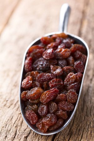 Photo for Raisins on metal scoop on wood (Selective Focus, Focus one third into the image) - Royalty Free Image