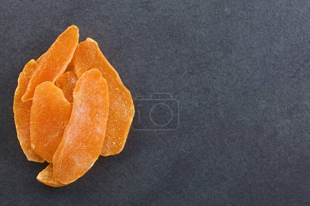 Photo for Dried candied mango fruit slices photographed overhead on slate with copy space on the side - Royalty Free Image