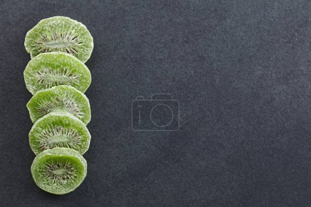 Photo for Dried candied kiwi fruit slices photographed overhead on slate with copy space on the side - Royalty Free Image