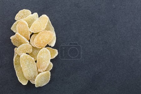 Photo for Sweet and spicy candied or crystallized ginger slices photographed overhead on slate with copy space on the side - Royalty Free Image