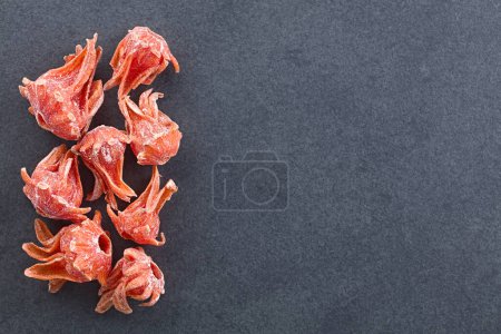 Photo for Crystallized candied red hibiscus flowers photographed overhead on slate with copy space on the side (Selective Focus) - Royalty Free Image
