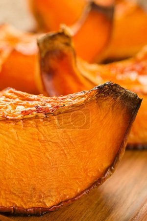 Photo for Sweetened baked pumpkin pieces on wooden board (Selective Focus, Focus on the front of the piece) - Royalty Free Image