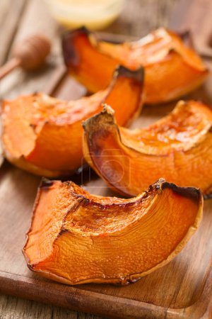 Photo for Sweetened baked pumpkin pieces on wooden board (Selective Focus, Focus on the front of the first piece) - Royalty Free Image