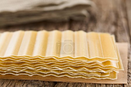 Photo for Dry uncooked ridged lasagna pasta sheets, photographed on wooden table (Selective Focus, Focus on the front edge of the sheets) - Royalty Free Image