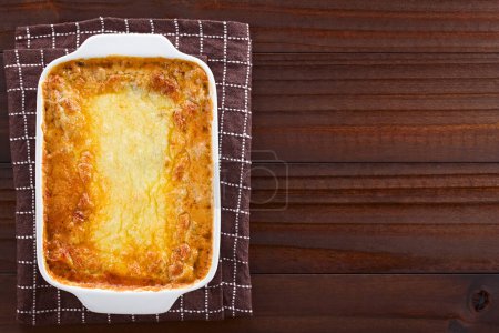 Photo for Freshly baked homemade lasagna or casserole dish with golden melted grated cheese on top, photographed overhead on wooden table with copy space on the side (Selective Focus, Focus on the dish) - Royalty Free Image