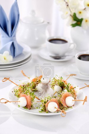 Foto de Appetizer quail egg stuffed with alfalfa sprouts with a slice of salmon, on a wooden skewer. Buffet serving for the Easter table. - Imagen libre de derechos
