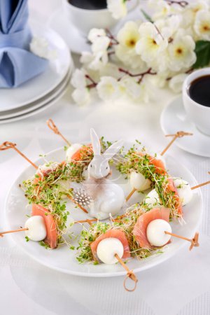 Foto de Appetizer quail egg stuffed with alfalfa sprouts with a slice of salmon, on a wooden skewer. Buffet serving for the Easter table. - Imagen libre de derechos