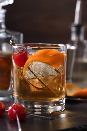 Foto de Cocktail Old Fashioned es una sofisticación anticuada de whisky y jarabe dulce. Servido con hielo, ralladura de naranja y cereza al maraschino. - Imagen libre de derechos