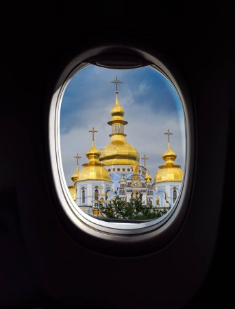 Photo for View from porthole window on golden domes of Cathedral of St. Michael's Monastery in Kyiv, Ukraine. Tourism concept for airlines company, air transportation and trip to Kyiv city. - Royalty Free Image