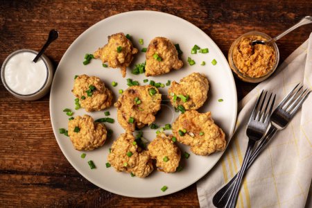 Photo for Cauliflower wings food. Pieces of cauliflower cooked in batter on a plate on a wooden background. Sprinkled with green onions. - Royalty Free Image