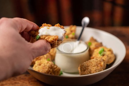 Photo for Cauliflower wings food. Pieces of flour-fried cauliflower with vegan sauces on a plate. A man's hand is holding a piece. - Royalty Free Image