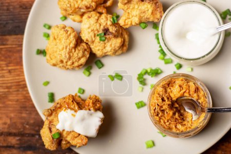 Photo for Cauliflower wings food. Pieces of flour-fried cauliflower with vegan sauces. Vegetarian food. - Royalty Free Image