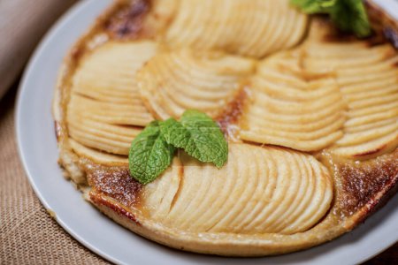 El pastel de manzana francés en su base de hojaldre crujiente son manzanas jugosas en rodajas mezcladas con azúcar morena, nuez moscada y otras especias. Decorado con hojas de menta.