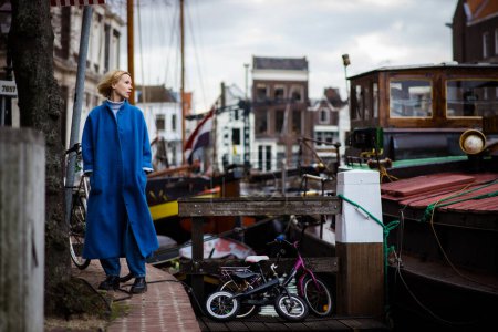 Téléchargez les photos : Femme touriste dans la baie avec des navires aux Pays-Bas. Paysage urbain de Rotterdam. Voyage et aventure. - en image libre de droit