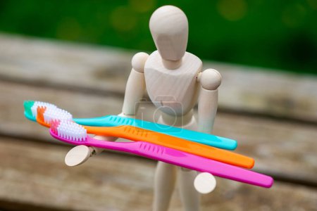 Téléchargez les photos : Brosses à dents multicolores dans les mains d'une figure humaine. Nettoyage et entretien des dents concept. - en image libre de droit