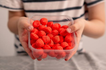 Photo for A glimpse into happiness: child's hands happily grabbing red fruity candies, a sweet testament to the love for chewy confections - Royalty Free Image