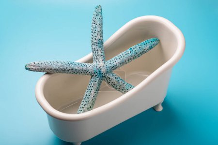 Photo for A starfish is in a bathtub. The bathtub is white and blue - Royalty Free Image