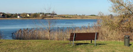 Téléchargez les photos : Espace détente avec banc au bord d'un lac printanier - en image libre de droit