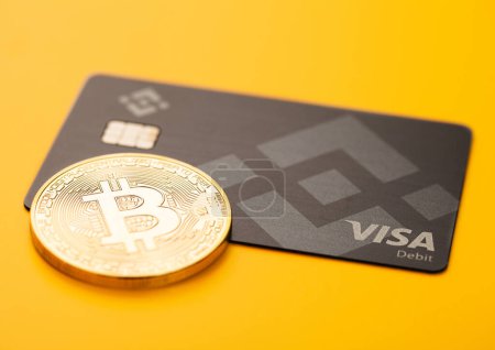 Photo for LONDON,UK - NOVEMBER 19, 2022: Binance visa credit card with bitcoin on yellow background. Cryptocurrency platform for trading and exchange. Top view - Royalty Free Image
