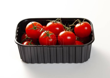 Foto de Bandeja de plástico con tomates rojos orgánicos crudos frescos sobre blanco. - Imagen libre de derechos