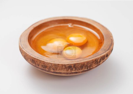 Foto de Tres yemas de huevo en plato de madera sobre fondo blanco. - Imagen libre de derechos