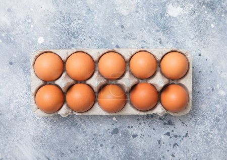 Photo for Raw brown organic eggs in paper tray on light kitchen background.Top view - Royalty Free Image