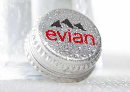 Foto de LONDON, UK - DECEMBER 29, 2022: Evian still natural water bottle cap with cold glass on white with dew. - Imagen libre de derechos