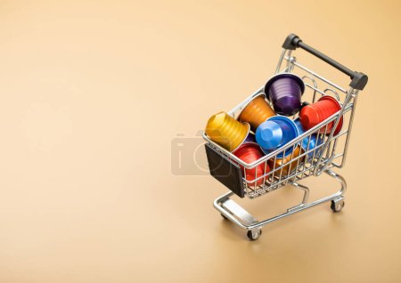 Photo for Shopping trolley with aluminium coffee capsules pods suitable for espresso machine on beige background.Top view. - Royalty Free Image