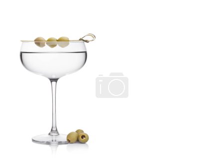 Téléchargez les photos : Cocktail de gin martini Vodka en verre cristal de luxe avec olives sur bâton de bambou avec olives vertes fraîches sur fond blanc. Espace pour le texte - en image libre de droit
