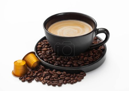 Foto de Taza de café con frijoles frescos crudos y cápsulas de café sobre blanco. Cremoso desayuno bebida casera - Imagen libre de derechos