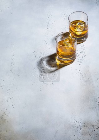 Photo for Two whiskey glasses with ice cubes on light background.Top view. - Royalty Free Image