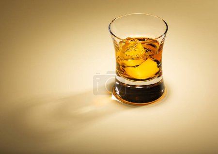 Téléchargez les photos : Verre à whisky single malt avec glaçons sur fond doré.Macro - en image libre de droit