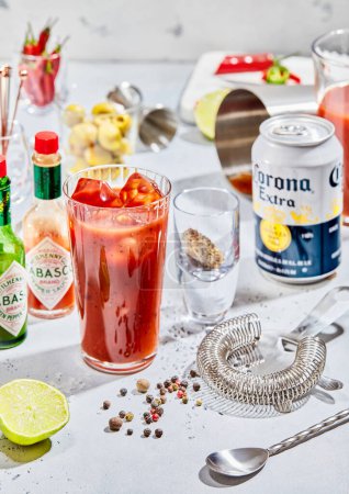 Photo for LONDON, UK - MARCH 12, 2023: Corona beer with bloody mary cocktail and tabasco with various bar utensil on light bar stand.Hard light - Royalty Free Image