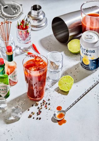 Foto de LONDRES, Reino Unido - 12 de marzo de 2023: Bloody mary cocktail with corona mexican beer and tabasco red and green hot sauce on light bar board. - Imagen libre de derechos