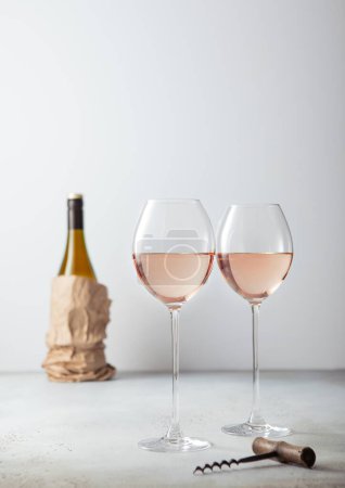 Téléchargez les photos : Verres roses de vin avec tire-bouchon et bouteille sur panneau lumineux. - en image libre de droit
