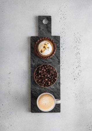 Foto de Tablero de mármol negro con tartaleta de caramelo de chocolate y taza de café. Vista superior. - Imagen libre de derechos