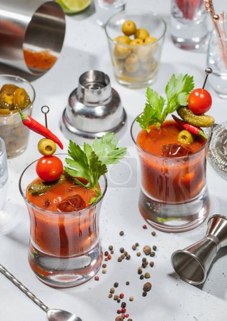 Téléchargez les photos : Verres à cocktail sanglants Mary avec shaker bar, jigger, cuillère à soupe de lumière aux olives et jalapeno. - en image libre de droit
