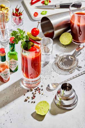 Photo for LONDON, UK - MARCH 15, 2023: Bloody mary cocktail with tabasco,strainer,shaker,lime and pepper on light board. - Royalty Free Image