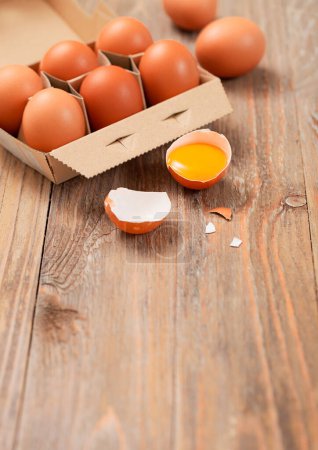 Photo for Brown raw farmers eggs in paper tray on light table with yolk and shell. Space for text - Royalty Free Image