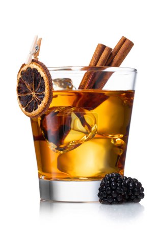 Téléchargez les photos : Cocktail de whisky à l'ancienne avec orange sèche, cannelle et mûres et gros glaçons sur blanc. - en image libre de droit