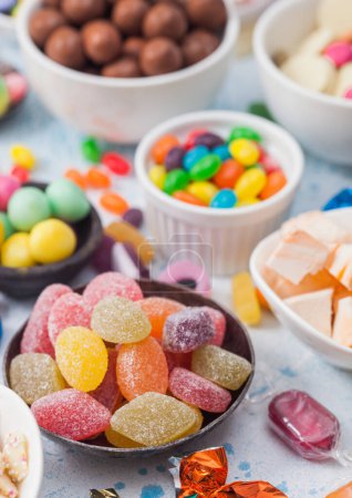 Téléchargez les photos : Bonbons sucrés gelée aux fruits et au chocolat au lait rubans sur fond de table bleu clair. - en image libre de droit